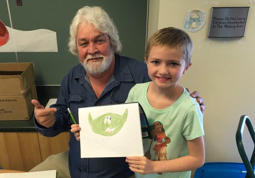 A young hospital patient smiling while holding a cartoon drawing